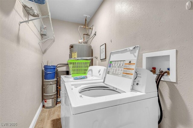 clothes washing area featuring light hardwood / wood-style floors, water heater, and washing machine and clothes dryer