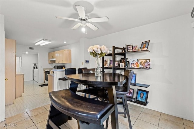 tiled dining space featuring washer and dryer and ceiling fan