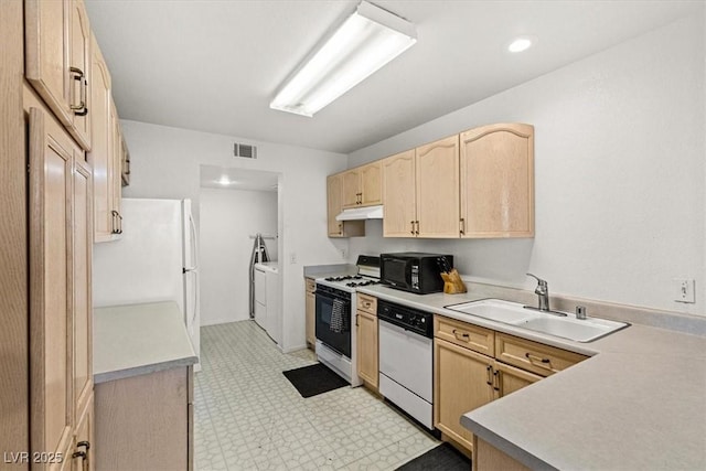 kitchen with light brown cabinetry, sink, white appliances, and independent washer and dryer