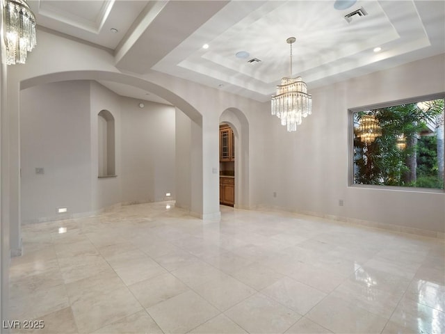 empty room featuring a raised ceiling and a notable chandelier