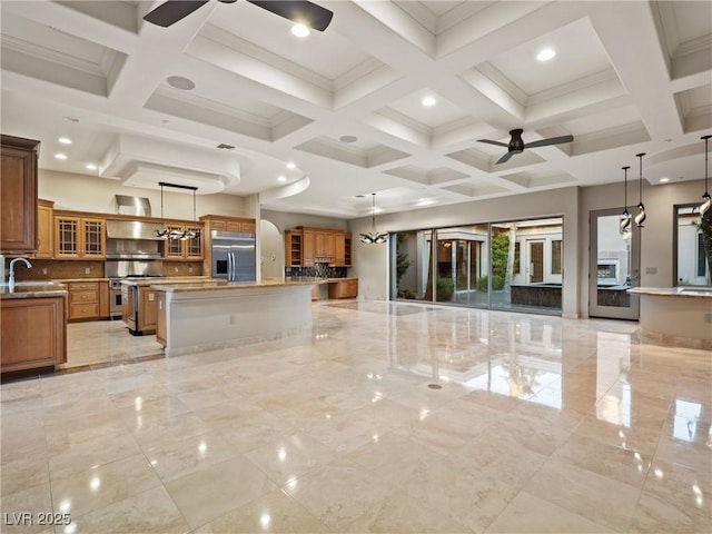 kitchen featuring stainless steel appliances, ceiling fan, a spacious island, sink, and hanging light fixtures