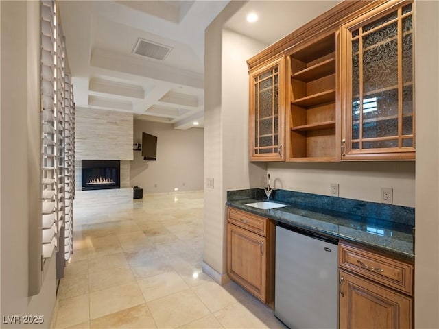 kitchen featuring dark stone counters, coffered ceiling, sink, fridge, and beamed ceiling