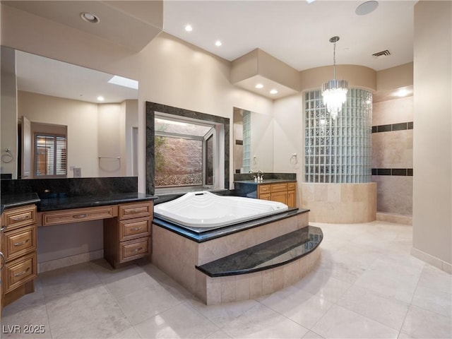 bathroom with a chandelier, vanity, tiled tub, and tile patterned flooring