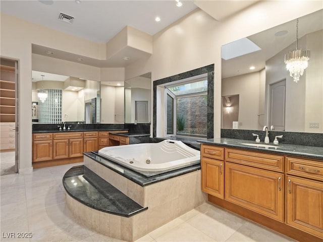 bathroom with tile patterned floors, vanity, a chandelier, and a relaxing tiled tub