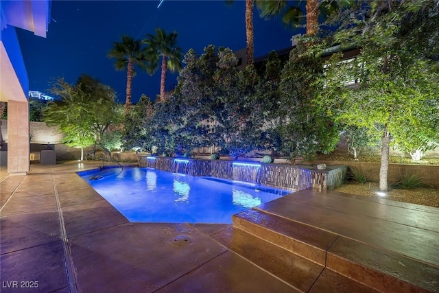 pool at twilight with pool water feature and a patio