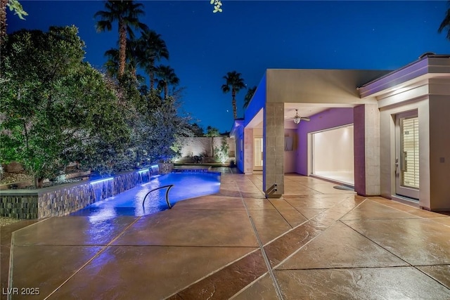 pool at twilight with pool water feature and a patio