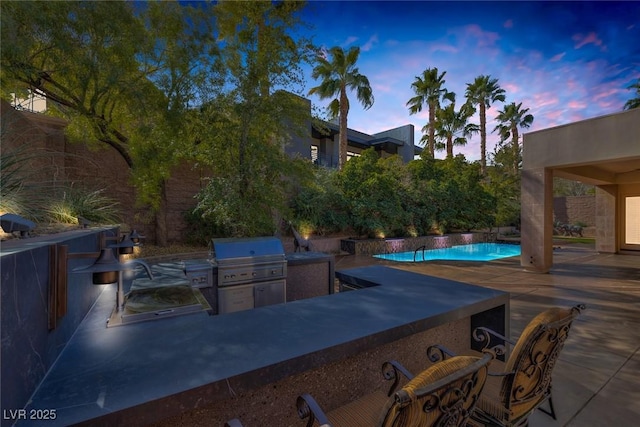 patio terrace at dusk with a grill and an outdoor kitchen