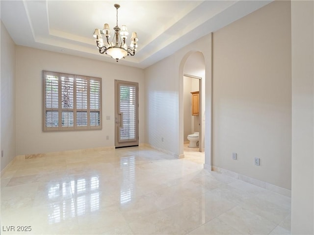 unfurnished room featuring a tray ceiling and an inviting chandelier