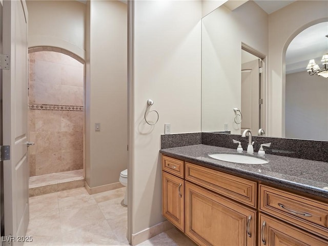 bathroom with a tile shower, vanity, toilet, and tile patterned floors