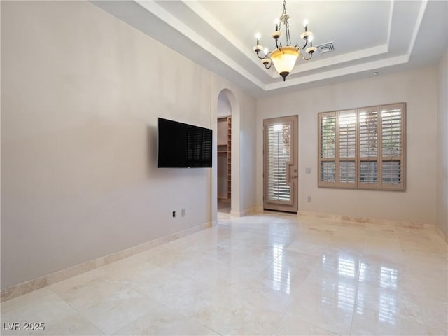 unfurnished living room with a notable chandelier and a tray ceiling