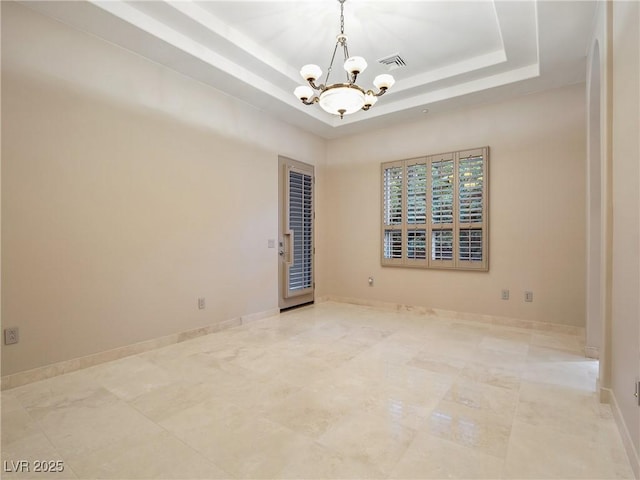 unfurnished room featuring a tray ceiling and an inviting chandelier