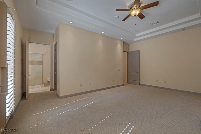 carpeted spare room featuring a tray ceiling and ceiling fan