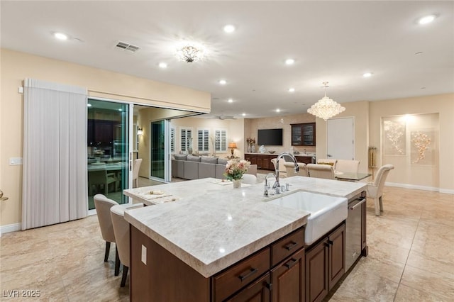 kitchen featuring a breakfast bar, sink, decorative light fixtures, a notable chandelier, and an island with sink