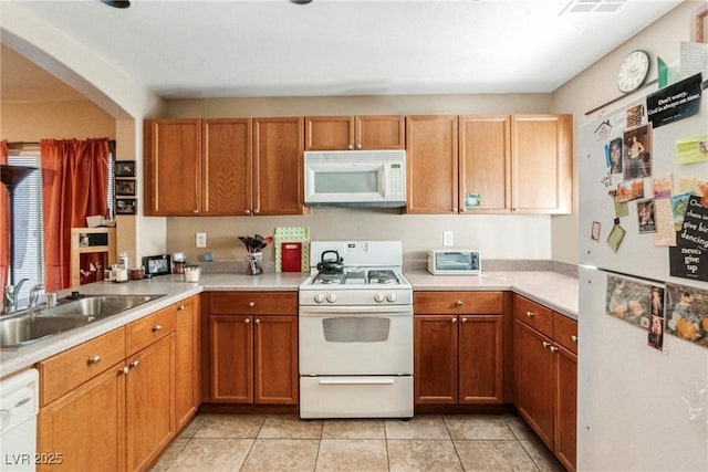 kitchen with kitchen peninsula, light tile patterned floors, white appliances, and sink