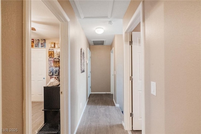 corridor with ornamental molding and hardwood / wood-style flooring