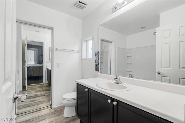 bathroom with hardwood / wood-style floors, vanity, toilet, and a shower