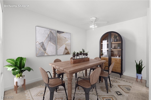 dining area featuring ceiling fan and light colored carpet