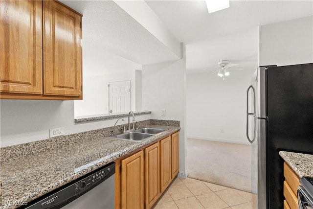 kitchen featuring ceiling fan, sink, light stone countertops, light colored carpet, and appliances with stainless steel finishes