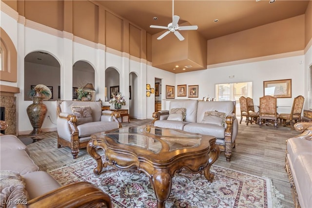 carpeted living room featuring a high end fireplace, ceiling fan, and a high ceiling