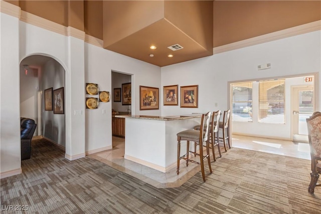 kitchen featuring carpet, a kitchen bar, and a high ceiling