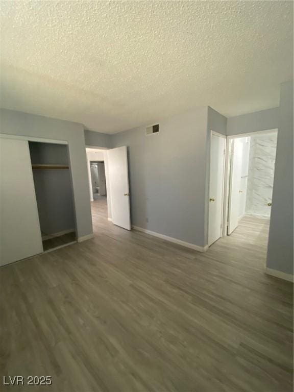 unfurnished bedroom with wood-type flooring, a textured ceiling, and a closet