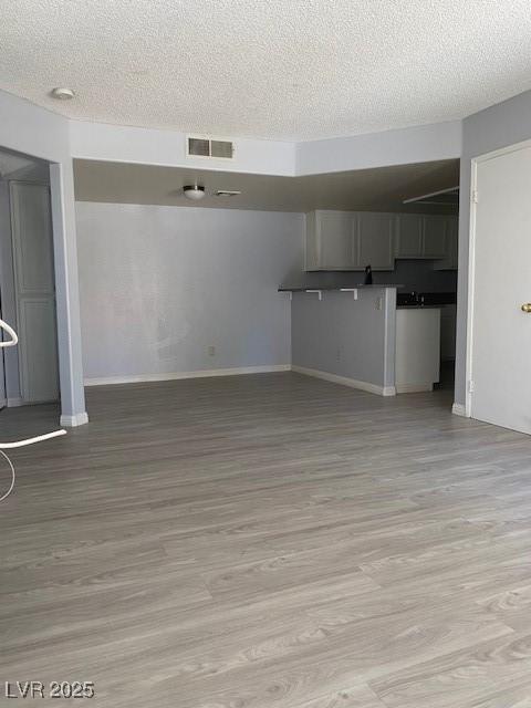 unfurnished living room featuring light hardwood / wood-style flooring and a textured ceiling