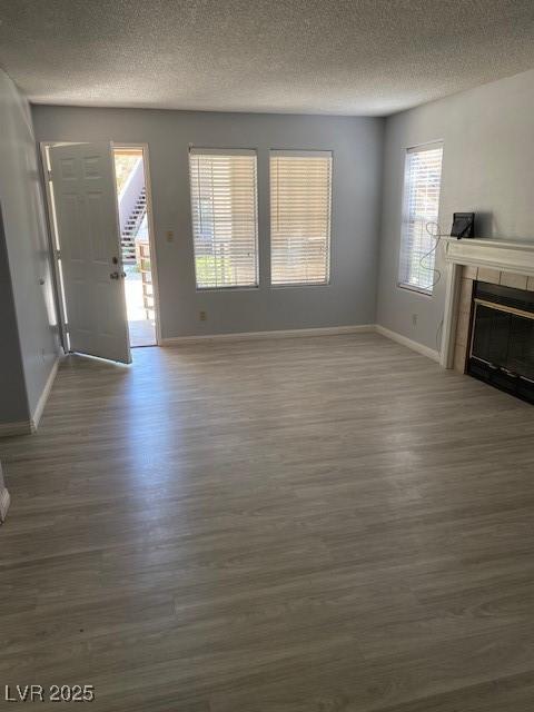 unfurnished living room featuring a fireplace, dark hardwood / wood-style flooring, and a healthy amount of sunlight