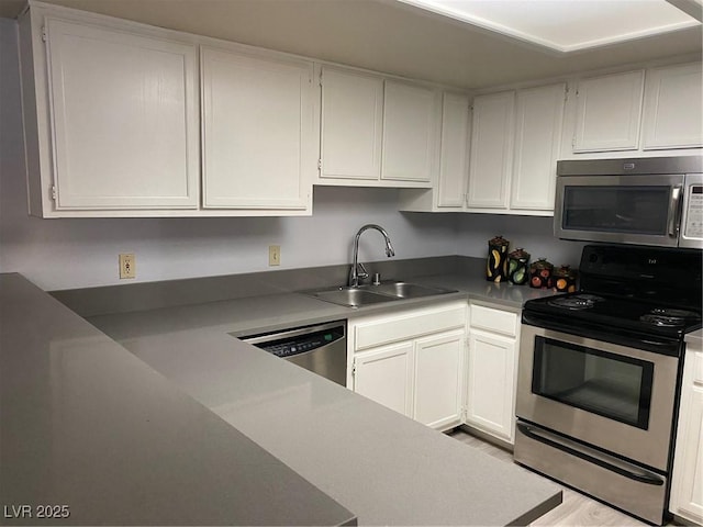 kitchen with white cabinets, appliances with stainless steel finishes, light wood-type flooring, and sink