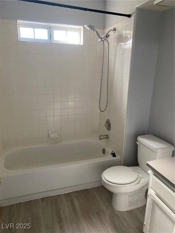 full bathroom with vanity, hardwood / wood-style flooring, toilet, and tiled shower / bath