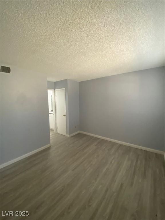 unfurnished room with a textured ceiling and dark wood-type flooring