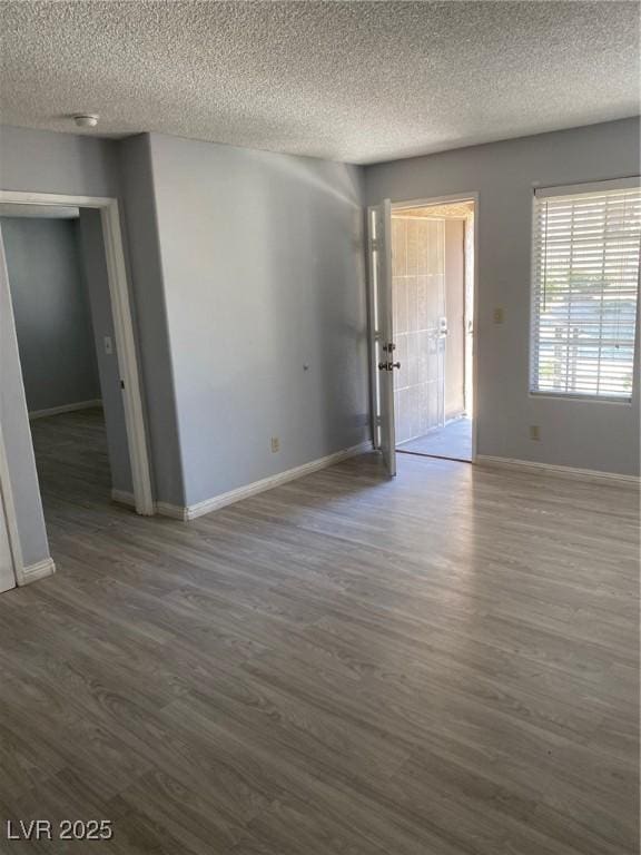 empty room featuring a textured ceiling and dark hardwood / wood-style floors