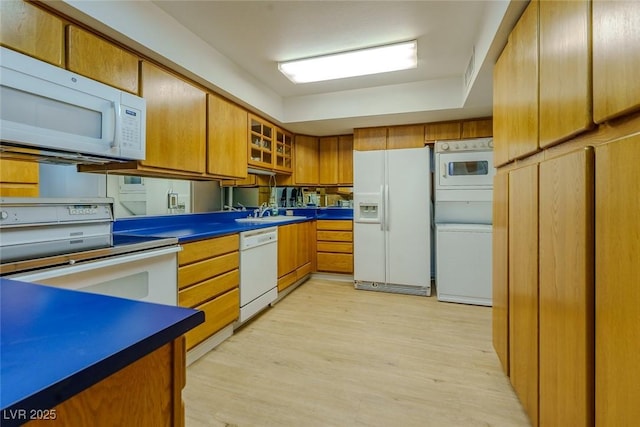 kitchen featuring light hardwood / wood-style floors, sink, white appliances, and stacked washer and dryer