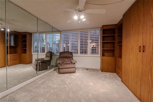 living area featuring a textured ceiling, light colored carpet, ceiling fan, and wooden walls