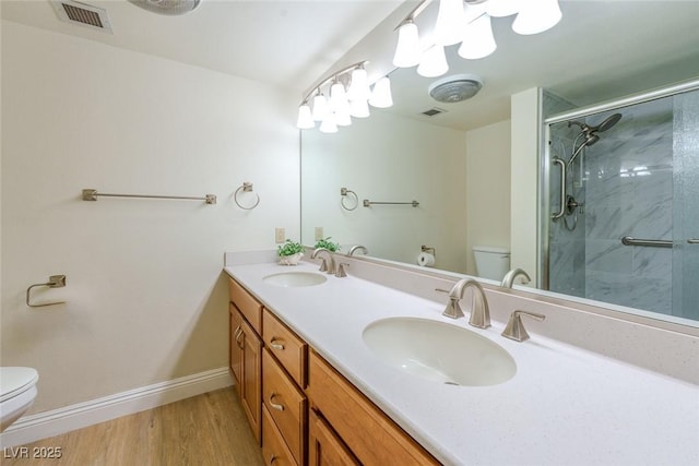 bathroom featuring hardwood / wood-style flooring, vanity, toilet, and a shower with shower door