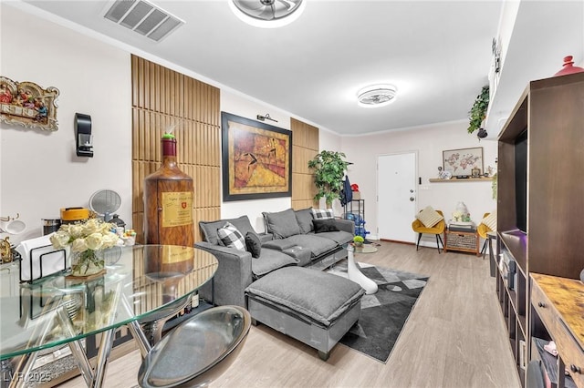 living room featuring visible vents, crown molding, and light wood-style flooring