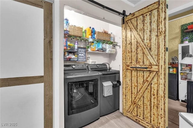 washroom with washer and dryer, wood finished floors, laundry area, and a barn door