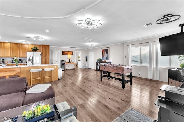 living area featuring light wood finished floors, visible vents, and attic access