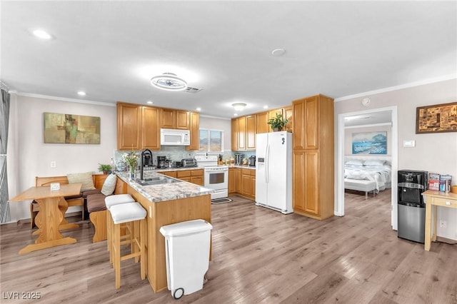 kitchen featuring a peninsula, white appliances, a sink, and crown molding