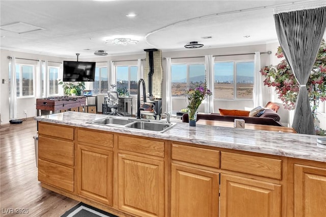 kitchen with light wood finished floors, light stone counters, open floor plan, and a sink