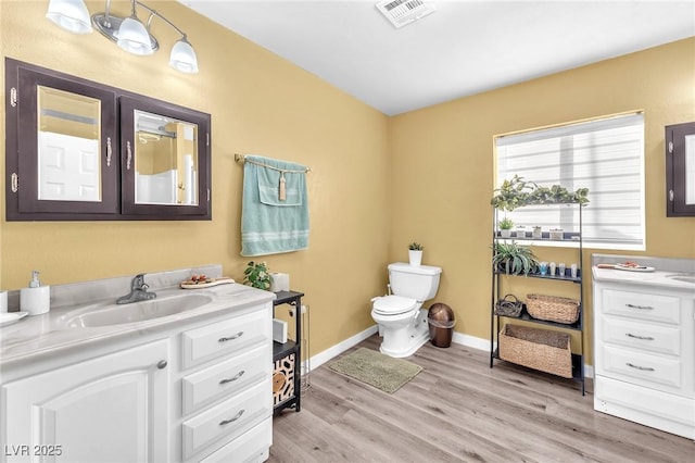 bathroom featuring visible vents, vanity, toilet, and wood finished floors