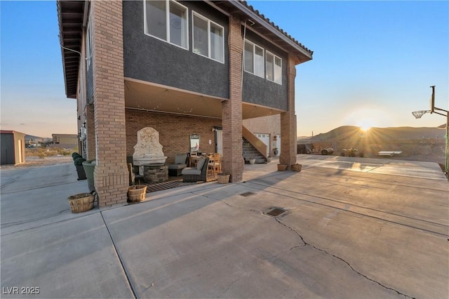 back of house at dusk with a patio and stucco siding