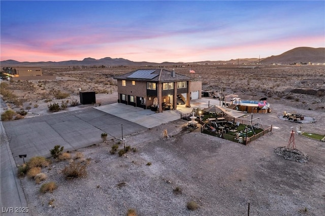 exterior space with a patio, a mountain view, a garage, solar panels, and concrete driveway