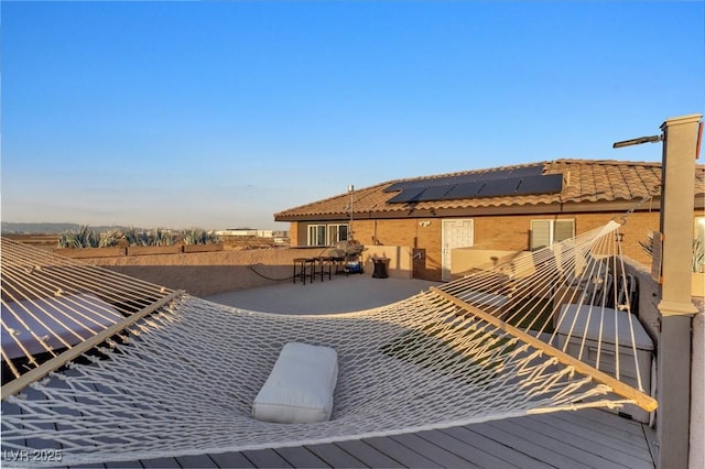 exterior space featuring brick siding, a tiled roof, and solar panels