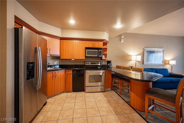 kitchen featuring kitchen peninsula, sink, light tile patterned floors, and stainless steel appliances