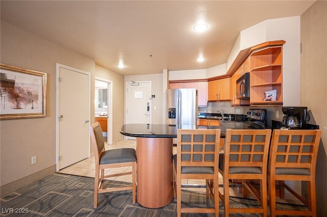 kitchen featuring sink, tile patterned floors, kitchen peninsula, a kitchen bar, and appliances with stainless steel finishes