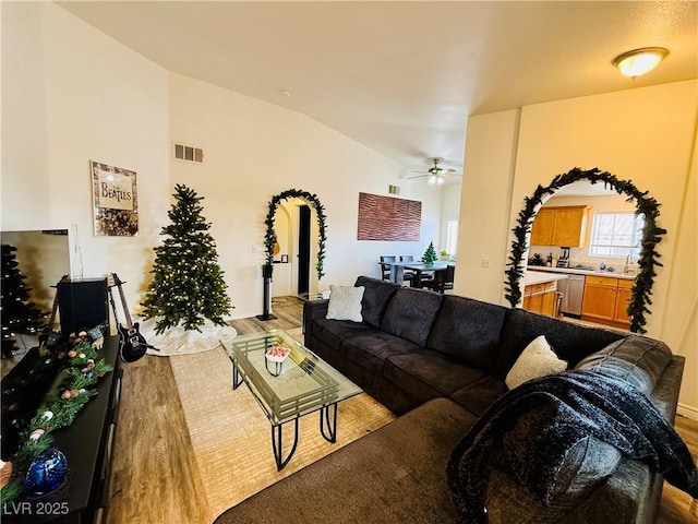 living room with ceiling fan, light hardwood / wood-style floors, and lofted ceiling