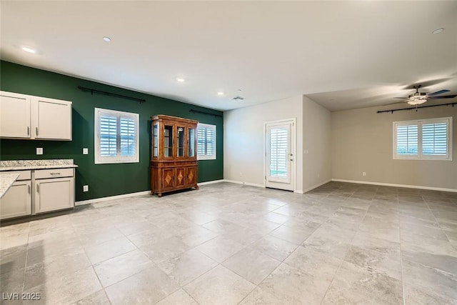 unfurnished living room featuring ceiling fan and a wealth of natural light