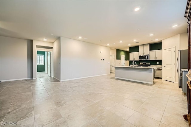 kitchen featuring sink, appliances with stainless steel finishes, and an island with sink