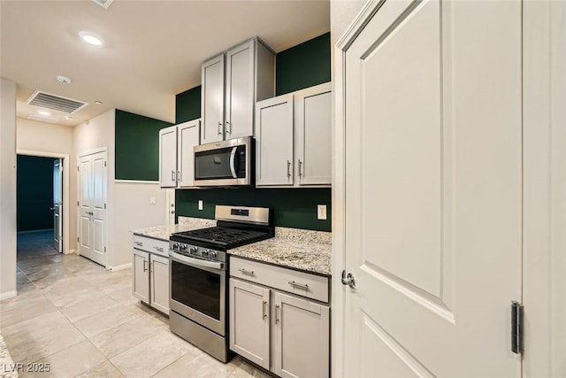 kitchen with light tile patterned floors, appliances with stainless steel finishes, and light stone counters