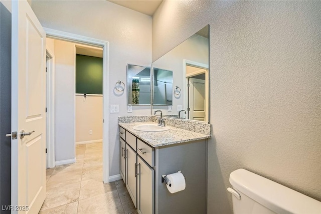 bathroom with toilet, vanity, and tile patterned flooring